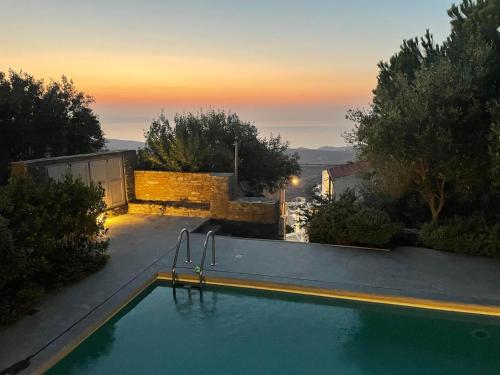 a swimming pool with a sunset in the background at AEGEAN WINGS MAISONETTE in Ioulida