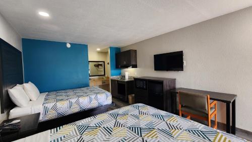 a hotel room with two beds and a desk and a tv at Scottish Inn & Suites in Wharton
