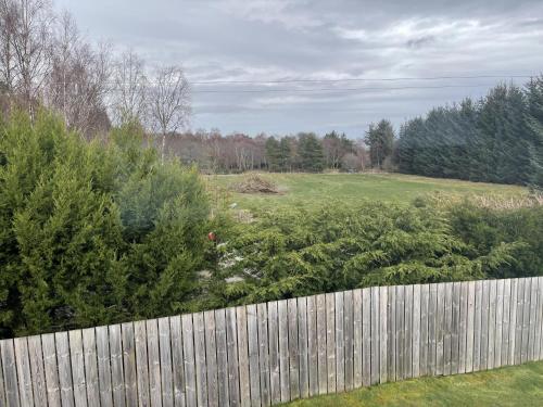 a fence in a yard with a field behind it at 4 Guests - Inverness Highland Hideaway Nc500 in Inverness