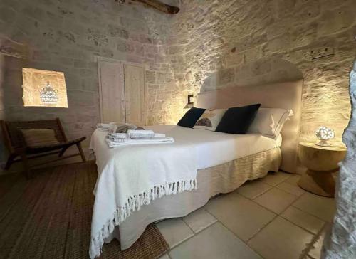 sypialnia z dużym łóżkiem w kamiennej ścianie w obiekcie Trullo Perla Greta - Luxury Country Villa & private heated pool w Alberobello