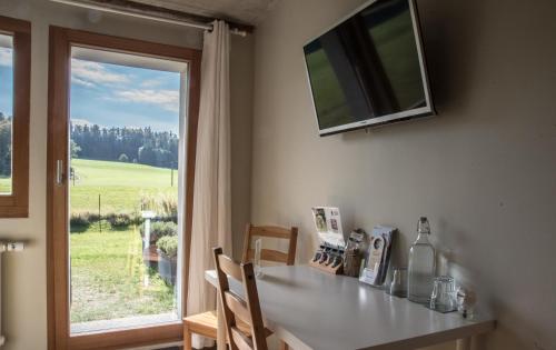 eine Küche mit einem Tisch mit Stühlen und einem Fenster in der Unterkunft Le Paysan Horloger in Les Bois