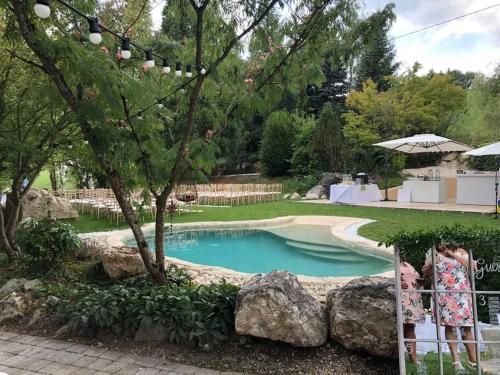 a woman standing next to a swimming pool in a yard at French Farmhouse between Lake & Mountain in Héry-sur-Alby