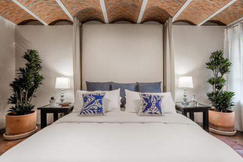a bedroom with a large bed with two plants at Casa Tranquilo, 4BR Home by Rosewood with Hot Tub in San Miguel de Allende
