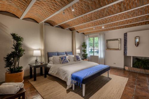 a bedroom with a large bed with a blue bench at Casa Tranquilo, 4BR Home by Rosewood with Hot Tub in San Miguel de Allende