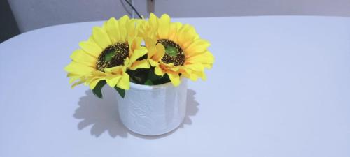 a white vase filled with yellow flowers on a table at Opal suites KE - South B in Nairobi