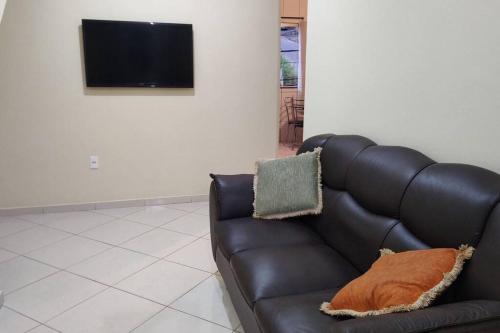 a black leather couch in a living room with a tv at Acomodação paraju-apartamento em caratinga in Caratinga