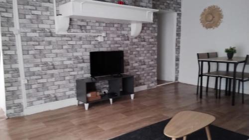ein Wohnzimmer mit Fernseher und einer Ziegelwand in der Unterkunft Maison de l'harmonie à Limoges in Limoges