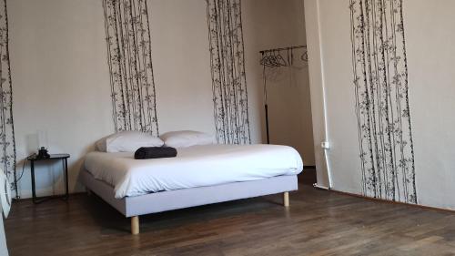 ein Schlafzimmer mit einem weißen Bett mit schwarz-weißen Vorhängen in der Unterkunft Maison de l'harmonie à Limoges in Limoges