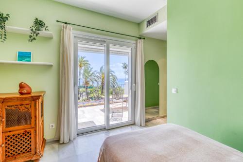 a bedroom with a bed and a sliding glass door at Hanami Alcazaba Beach Duplex Sea View in Estepona