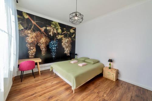 1 dormitorio con 1 cama y una pintura de uvas en La maison Grand Cru en Arveyres