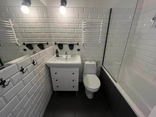 a white bathroom with a toilet and a sink at Apartament Śródmieście Krosno in Krosno