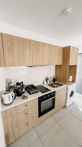 a kitchen with wooden cabinets and a stove and a sink at WAKE UP BY THE SEA FLATS in Protaras