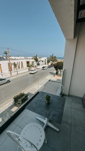 a table and chairs on a balcony with a view of a street at WAKE UP BY THE SEA FLATS in Protaras