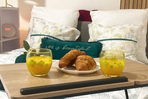een dienblad met croissants en jus d'orange op een bed bij Le Mini SweetHome - Bobigny- Porte de Paris in Bobigny