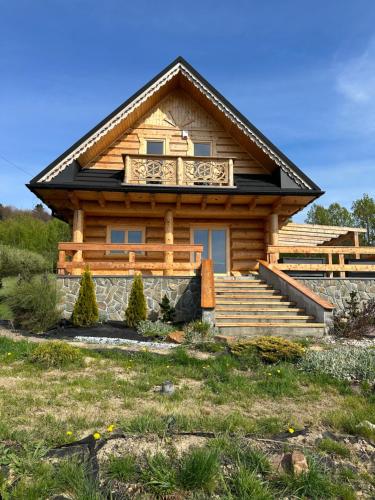 eine Blockhütte mit einer Veranda und einer Treppe vor dem Haus in der Unterkunft Siedlisko Huta Szklana in Bieliny