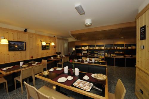 a restaurant with tables and chairs and a kitchen at Hotel Garni Pegrà in Ponte di Legno