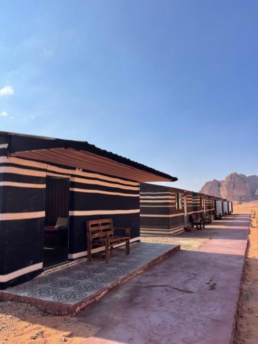 uma fila de cabanas com um banco ao lado em Wadi Rum Magic Camp em Wadi Rum