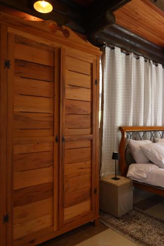 a bedroom with a large wooden closet next to a bed at Aldeia Flor de Liz - Pedra Azul in Pedra Azul