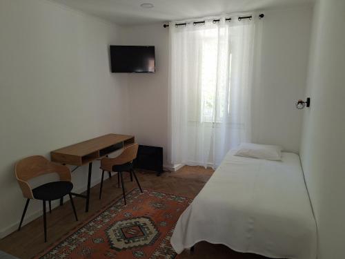 a bedroom with a bed and a desk and a television at Penaferrim Sintra Rooms in Sintra
