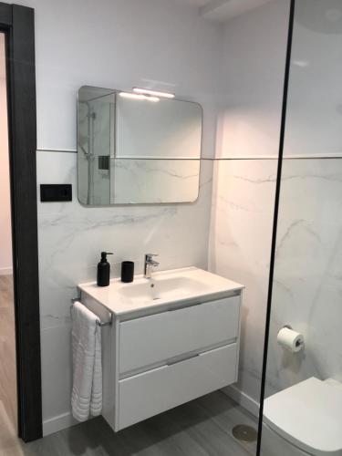 een witte badkamer met een wastafel en een spiegel bij A Neida Casa con terraza con vistas al mar in Cee