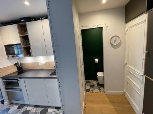 une cuisine avec une porte menant à une salle de bains. dans l'établissement Double appartement - Le Marais, à Paris