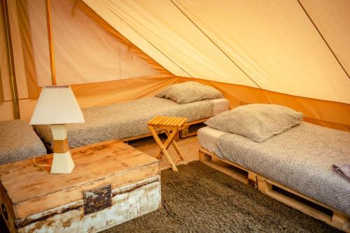 a tent with two beds and a table with a lamp at The Glamping Spot - Douarnenez in Plonévez-Porzay