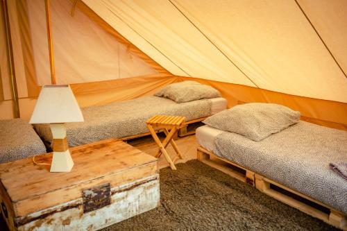 坡隆维茨普尔扎伊The Glamping Spot - Douarnenez的有两张床和一张带灯的桌子的帐篷