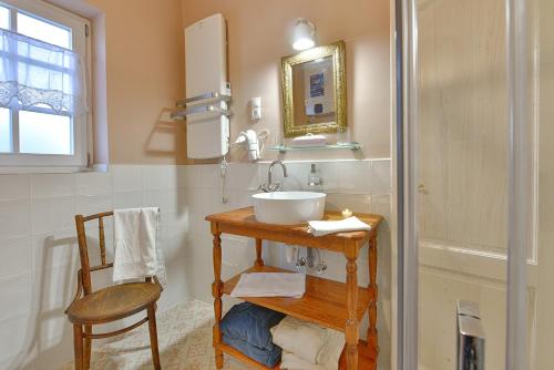 a bathroom with a sink and a chair at Kökényház vendégház in Kötcse