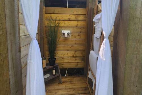 a bathroom with wooden walls and a shower with white curtains at The Fox Den in Delta