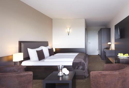 ビューズムにあるnordica Hotel Friesenhofのベッド1台と椅子2脚が備わるホテルルームです。