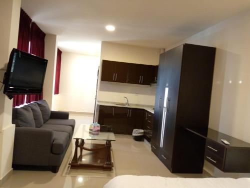 a living room with a couch and a tv and a kitchen at Monument Suites in Amman