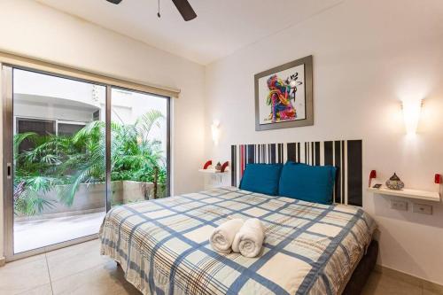 a bedroom with a bed with blue pillows and a window at Skyline by Zama Homes in Playa del Carmen