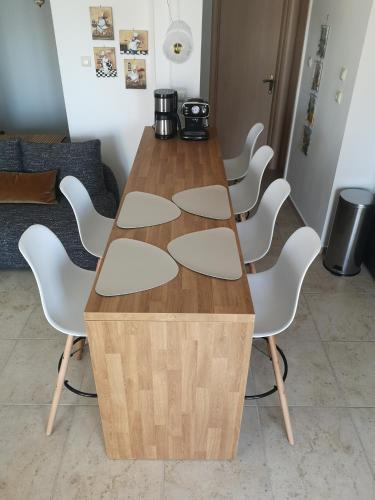 a wooden table with white chairs around it at Απέραντο γαλάζιο Le grand blue in Mola Kalyva