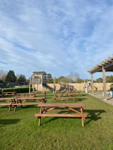 a group of picnic tables in a park with a playground at Private luxury lodge Hafan y Mor Gwynedd North Wales LL53 6HX in Chwilog