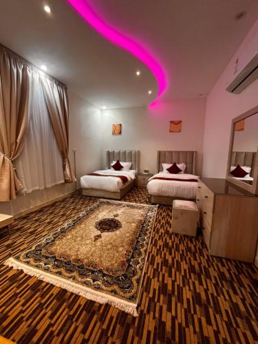 a bedroom with two beds and a pink lighting at شقق الروشن الجوفي in Al Fayşalīyah