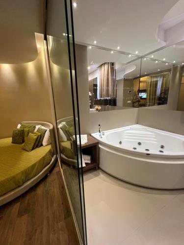 a bathroom with a tub and a bed in it at Hotel Smeraldo in Qualiano