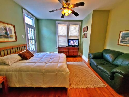 Point Breeze Guest House في بيتسبرغ: غرفة نوم بسرير واريكة ومروحة سقف