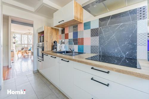 une cuisine avec des armoires blanches et un comptoir dans l'établissement Beau T3-résidence calme-proche Paris/La Défense, à Suresnes