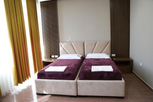 Rezidenca Arlington في بيرات: غرفة نوم مع سرير كبير مع ملاءات أرجوانية