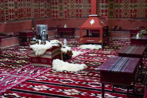 Zimmer mit einem Boden mit einem Teppich mit einem Tisch und einem Zimmer mit in der Unterkunft sunset camp&jeep tour in Wadi Rum