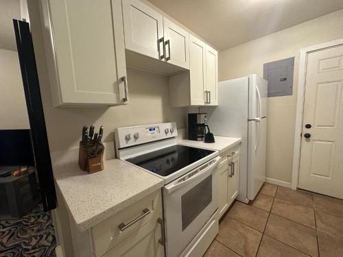 a kitchen with white cabinets and a white refrigerator at Waimanalo Beach Cottages in Waimanalo