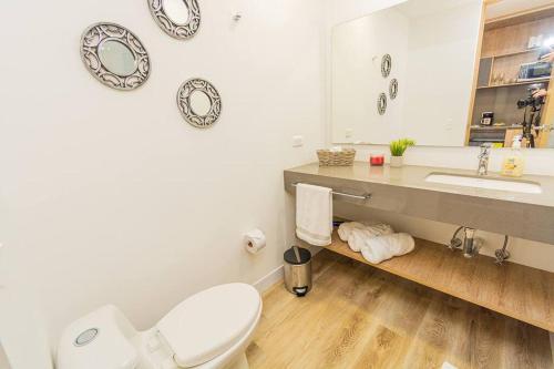 een badkamer met een toilet, een wastafel en een spiegel bij Bright Studio Topfloor A/C, Poblado Coworking1412 in Medellín