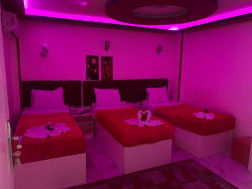 a room with two beds and pink lighting at Salvatore Room With Simple Breakfast- Al Dokki in Cairo