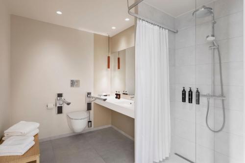 a white bathroom with a shower and a sink at Residence Inn by Marriott Copenhagen Nordhavn in Copenhagen
