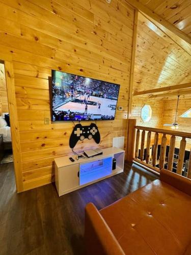 a living room with a television in a wooden cabin at New! Indoor Pool/PS 5/Hot tub/Parkway in Pigeon Forge