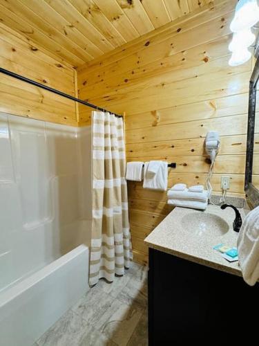 a wooden bathroom with a tub and a sink at New! Indoor Pool/PS 5/Hot tub/Parkway in Pigeon Forge