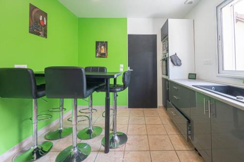 une cuisine avec des murs verts et une table et des chaises noires dans l'établissement *Disneyland-Paris à 20 min* 11 pers, Golf, Billard, à Guermantes