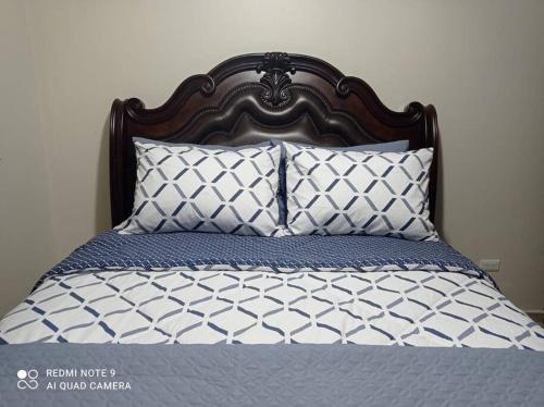 a bed with a wooden head board and pillows at Grupo Gailla Departamento in Mexico City