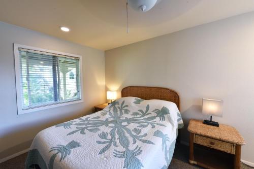 a bedroom with a bed and two lamps and a window at Waimanalo Beach Cottages in Waimanalo