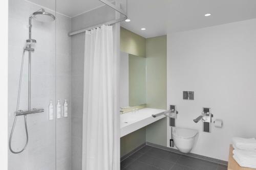 y baño con ducha, aseo y lavamanos. en Fairfield by Marriott Copenhagen Nordhavn, en Copenhague